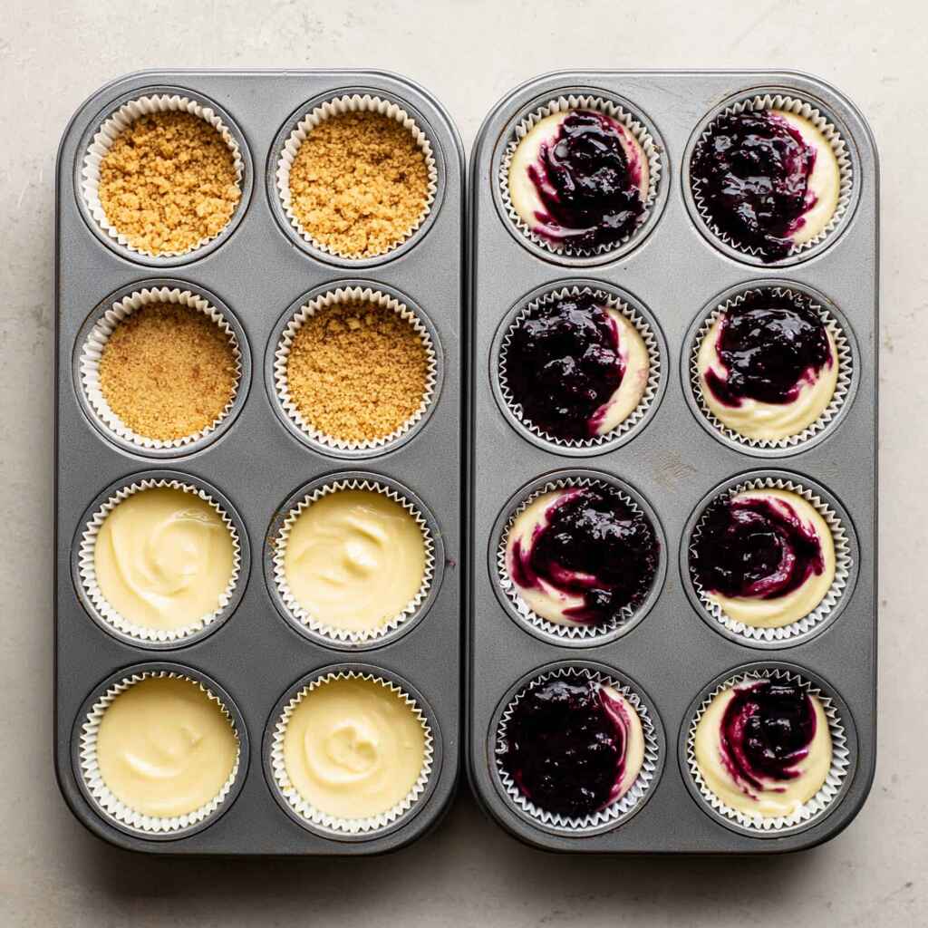Mini blueberry cheesecakes in muffin tin before baking, showing crust and swirl stages