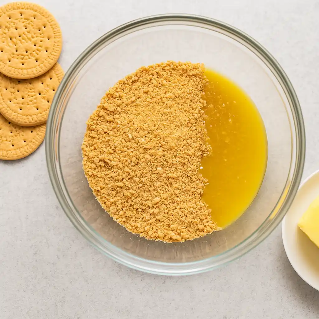 Mixing graham cracker crumbs with melted butter for cheesecake crust